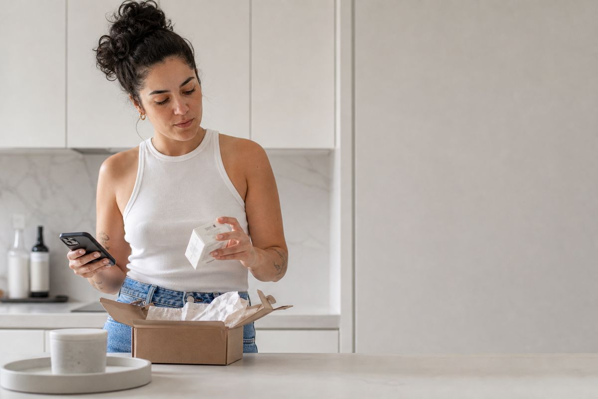 Testadora abrindo na cozinha a caixa que acabou de chegar